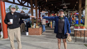 Two men stand beside each other with arms extended sideways, but not touching, to demonstrate proper social distancing at a farmers market during the COVID-19 pandemic. Photo by Debbie Roos, North Carolina Cooperative Extension.